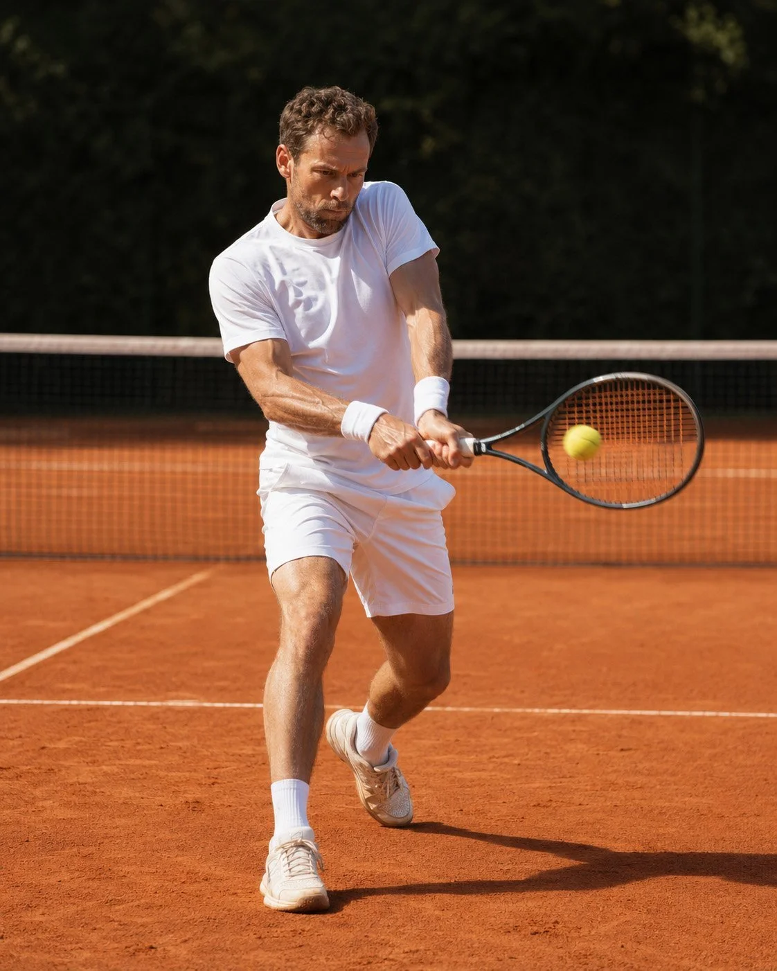 Tennisspieler bei einer zweihändigen Topspin-Rückhand auf dem Sandplatz